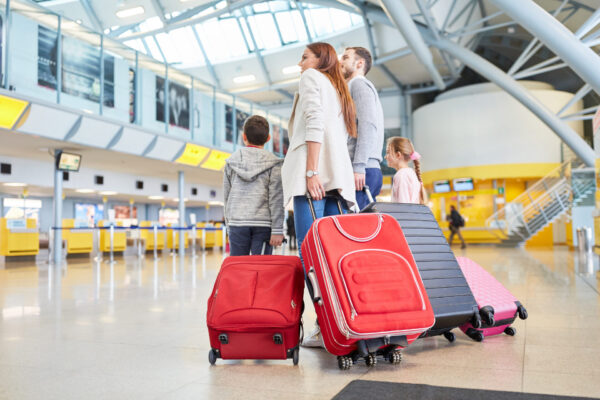 Family and children with many suitcases in the airport terminal are waiting for the connecting flight